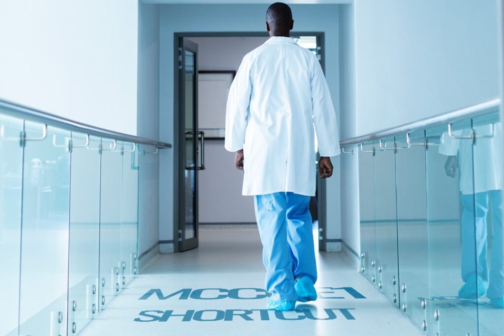 A doctor in a white coat and blue scrubs walks down a hallway with glass railings, with "Quick Shortcut for MCCQE1 Success" marked on the floor.