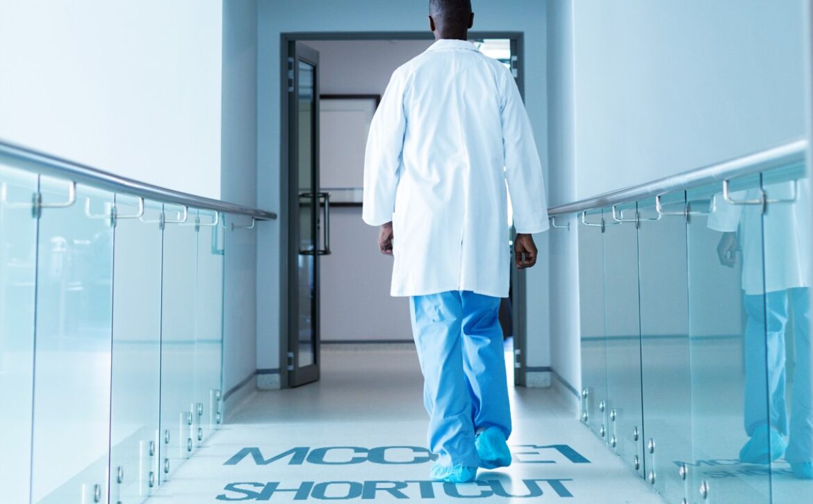 A doctor in a white coat and blue scrubs walks down a hallway with glass railings, with "Quick Shortcut for MCCQE1 Success" marked on the floor.