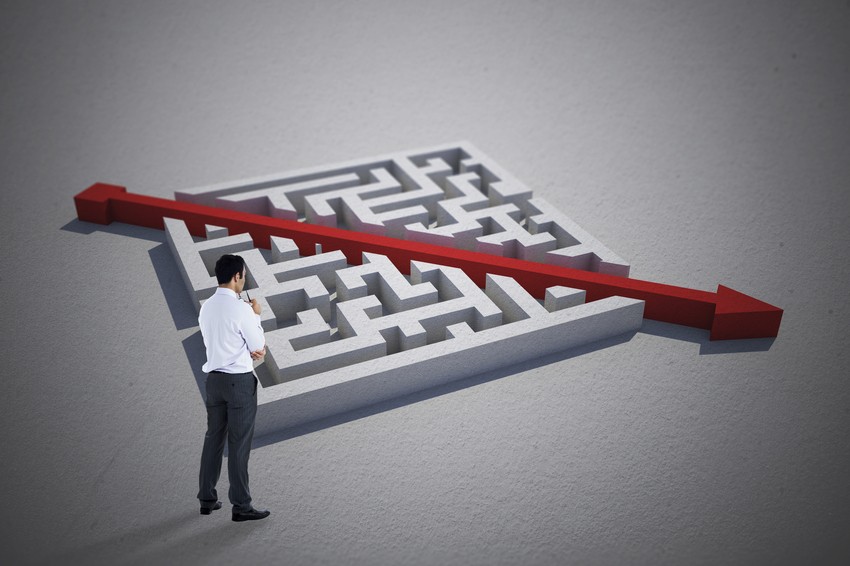 A person in medical attire ponders while looking at a large maze with a red arrow cutting straight through it, symbolizing the clarity and direction provided by Ace QBank for MCCQE1 exam preparation.