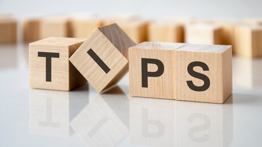 Wooden blocks spelling "TIPS" are arranged on a glossy surface, with other blurred blocks in the background, offering insights for effective MCCQE1 exam preparation.