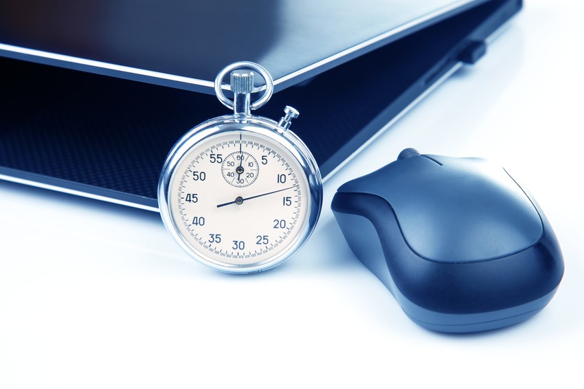 A stopwatch and a computer mouse are placed next to a closed laptop, perfect tools for efficient MCCQE1 exam preparation with Ace QBank.