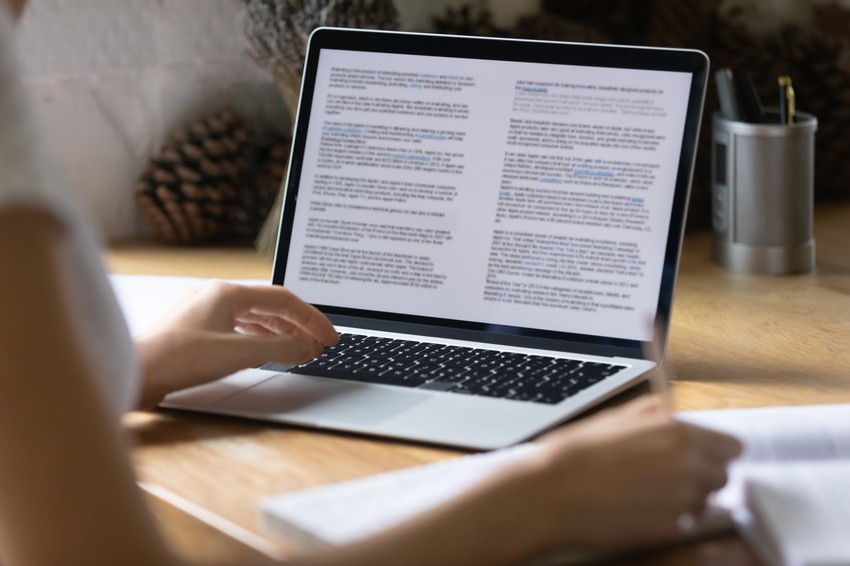 A person reading Canadian guidelines on a laptop at a wooden desk, with a notebook and pen nearby.