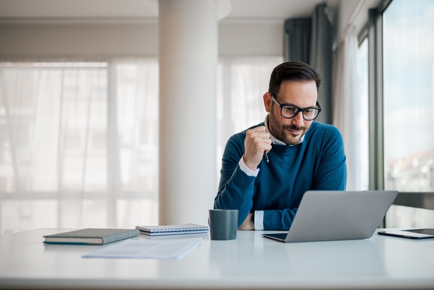 A man sits at a desk, intently reviewing the Canadian guidelines on his laptop. Nearby, a notebook rests beside an Ace QBank study guide, hints at his preparation for the MCCQE1 exam.