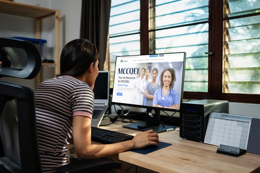 A person in a striped shirt sits at their desk, focused on the computer screen that displays an Ace QBank Update for MCCQE1, diligently studying for the medical exam.