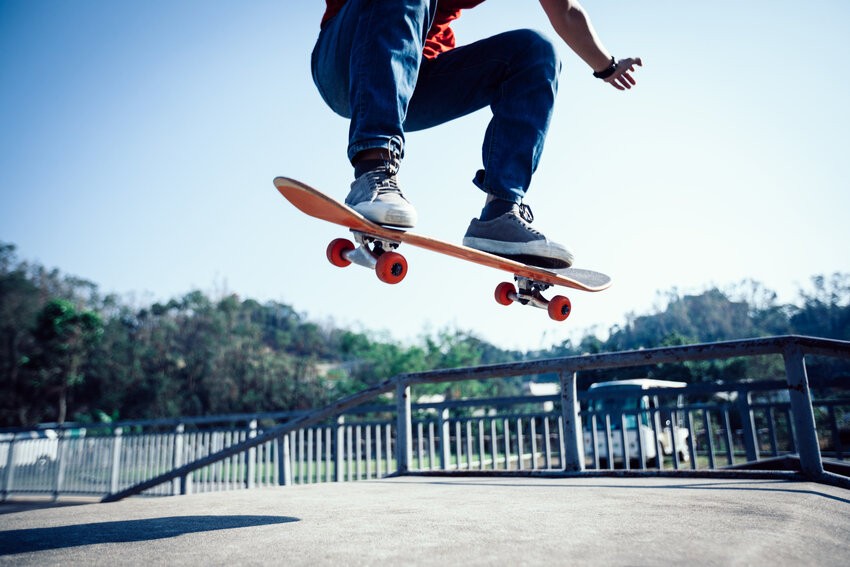 Skateboarder performing an airborne trick above a railing in a skate park, wearing a red shirt and blue jeans, with a clear blue sky in the background - Ace QBank clinical edge