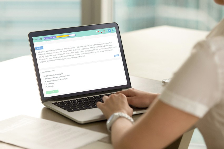 A person sits at a desk near a window, using a laptop with the Ace QBank webpage open. The screen displays text and options, likely related to Canadian guidelines for the MCCQE1 exam.