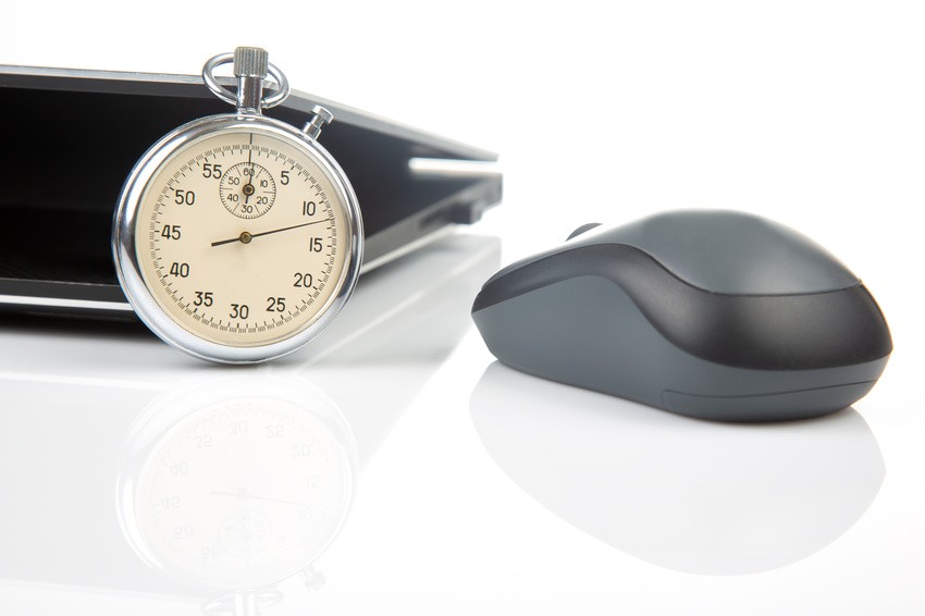 A stopwatch and a computer mouse rest on a white surface next to a partially visible laptop, ready for anyone using Ace QBank to tackle the new MCCQE1 format.