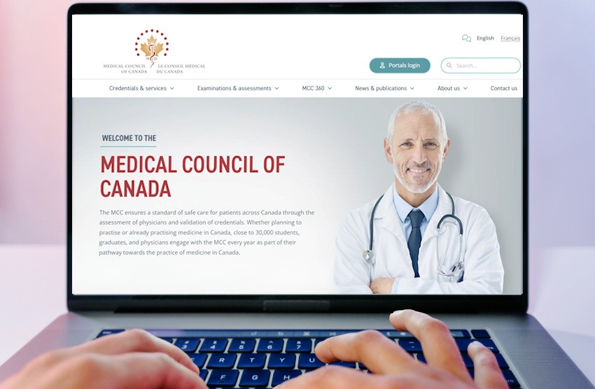 A doctor in a white coat types on a laptop, engrossed in the MCC website. The screen hints at discovering "MCCQE1 Exam Passing Secrets for 2025," showcasing dedication to mastering medical knowledge.