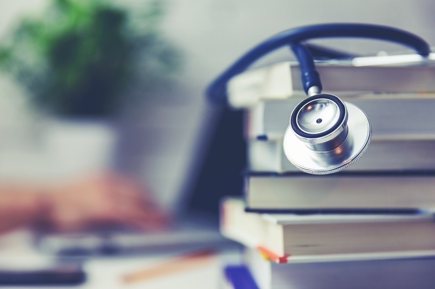 A stethoscope rests on a stack of books, symbolizing the dedication needed for AMC Exam Preparation.