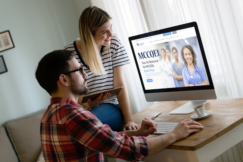 A man and woman examine a computer screen showing a website titled "MCCQE1," displaying an image of a woman in scrubs. The site highlights crucial MCCQE1 exam dates alongside access to a comprehensive question bank.